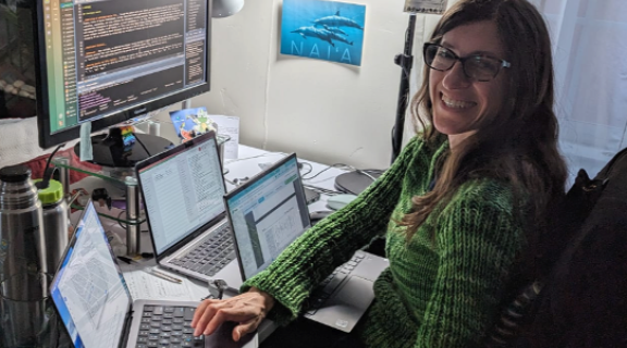Paula in green sweater sitting at desk