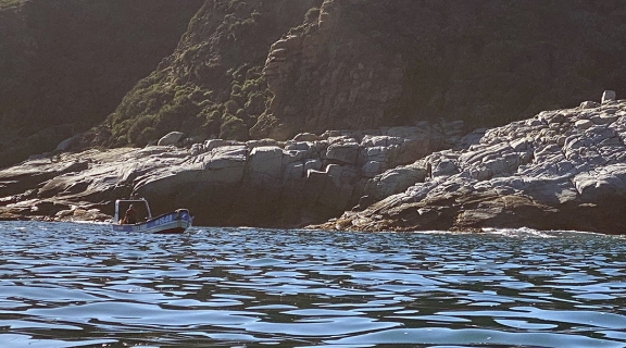 Small scale commercial fisher boat in water along shoreline, Chile